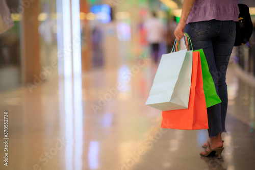 Women carrying a lot of colorful shopping bags in blurred shopping mall