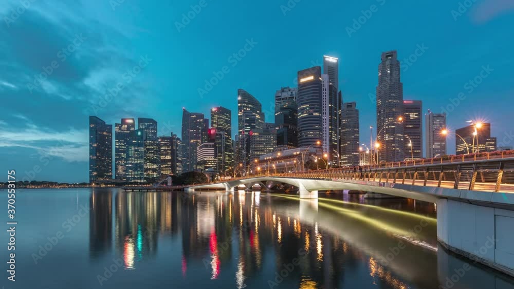 Esplanade bridge and downtown core skyscrapers in the background Singapore night to day transition timelapse. Illuminated towers reflected in water Esplanade bridge and downtown core skyscrapers in the background Singapore night to day transition timelapse. Illuminated towers reflected in water