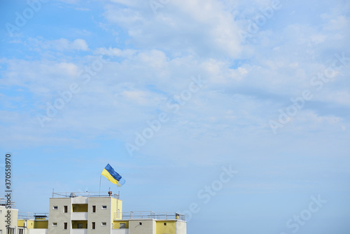 National blue and yellow flag of Ukraine waving on top of high apartment building for independence day celebration. Flag day. National symbols of country.