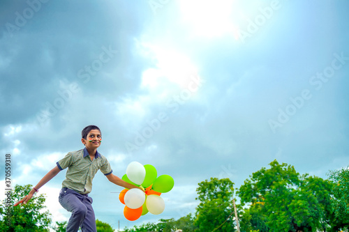 little indian school boy Jumping in sky with tri color balloons and celebrating Independence or Republic day of India