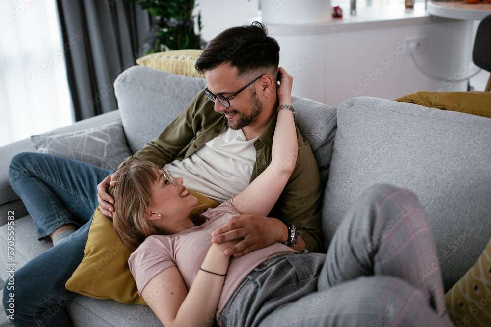 Husband and wife enjoying on sofa. Happy couple relaxing in living room.. Husband and wife enjoying on sofa. Happy couple relaxing in living room..