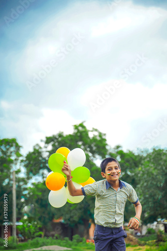 little indian school boy Jumping in sky with tri color balloons and celebrating Independence or Republic day of India