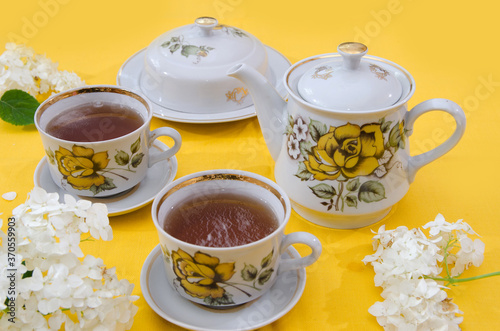 tea set, tea party. traditional table with porcelain teapot, cups and sugar pot. yellow background.