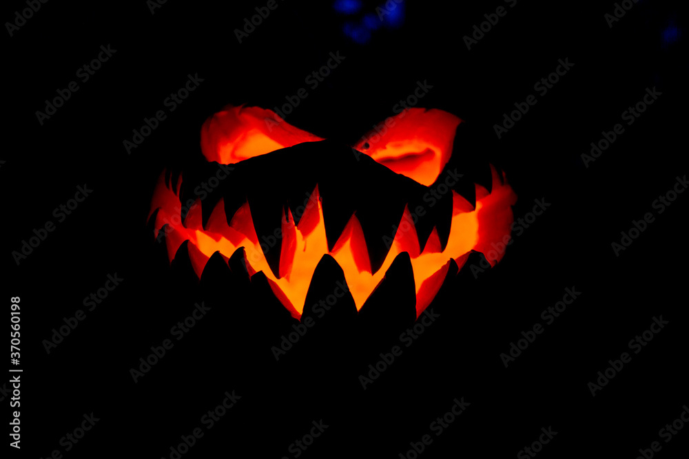 Fototapeta premium An evil winking hand-carved pumpkin frightening at Halloween