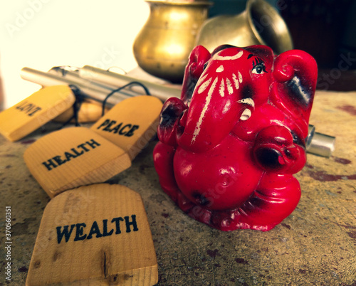 Red ganesh deva sculpture portrait picture with pots and Bells in the background. Lord Ganesh is one of the important and prestigious figure in Hindu mythology