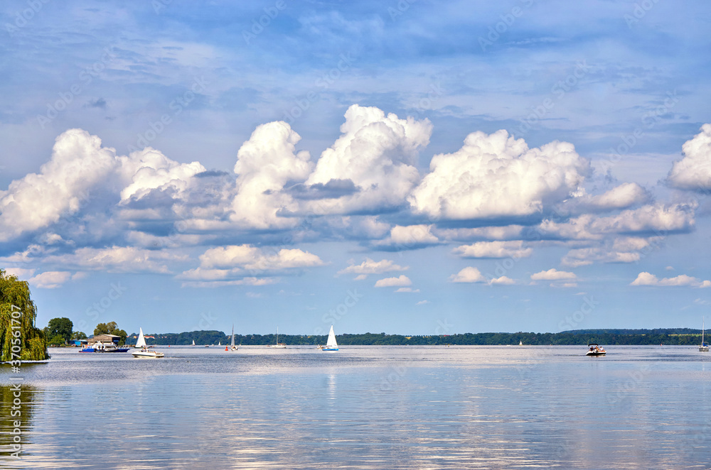 Sky with gigantic clouds over a lake with sailing boats and motor boats.