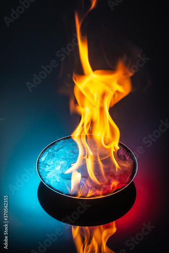 modern frying pan with liquid flaming on dark background, close view 