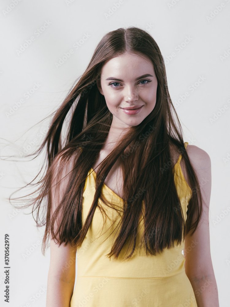 Beautiful brunette with long smooth hair in yellow shirt natural portrait over white background