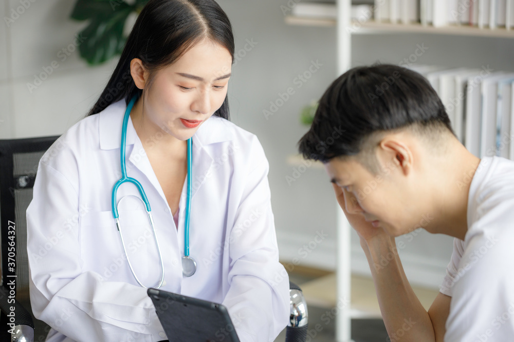 Beautiful young Asian female doctor is recording a medical history on the clipboard and explaining something to the male patient. Medical and health care concepts Beautiful young Asian female doctor is recording a medical history on the clipboard and explaining something to the male patient. Medical and health care concepts