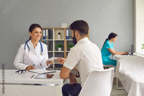 The doctor gives the patient a prescription while sitting at the table in the office of the clinic.Medical consultation.