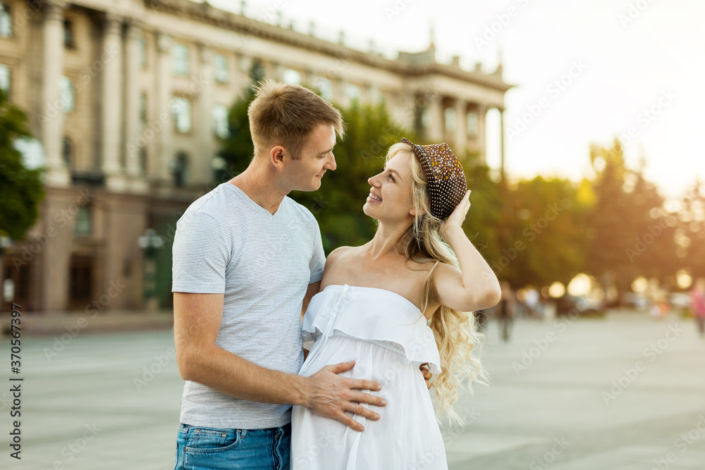 pregnant woman and her boyfriend walking in the city square. pregnant woman and her boyfriend walking in the city square.