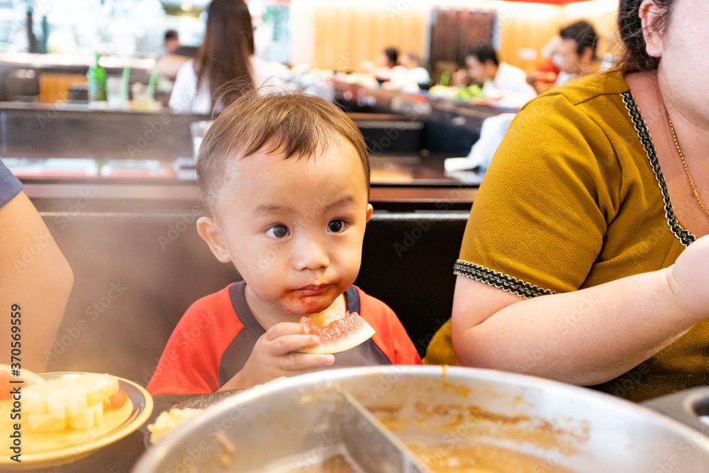 Little adorable Asian boy eating watermelon in restaurant Little adorable Asian boy eating watermelon in restaurant