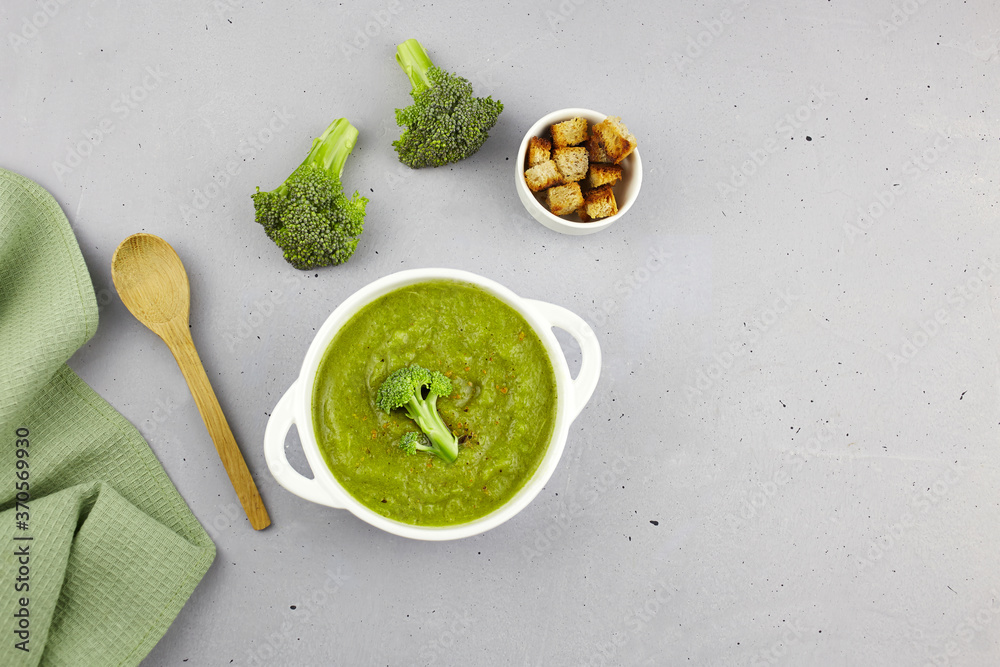 Broccoli cream soup with croutons in a plate on a grey background. Vegetarian and vegan food. Top view with copy space. Broccoli cream soup with croutons in a plate on a grey background. Vegetarian and vegan food. Top view with copy space.