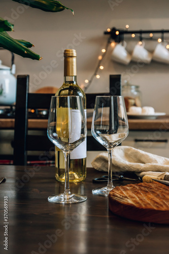 Wine bottle and two glasses on kitchen background.