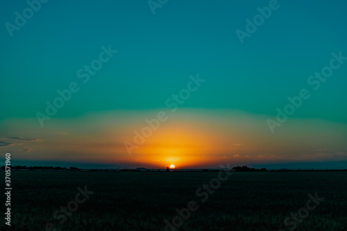 Beautiful evening sunset over a field of Golden ears of wheat and barley. Yellow is the rich color of the Sunny sky and wide spacious meadows with crops