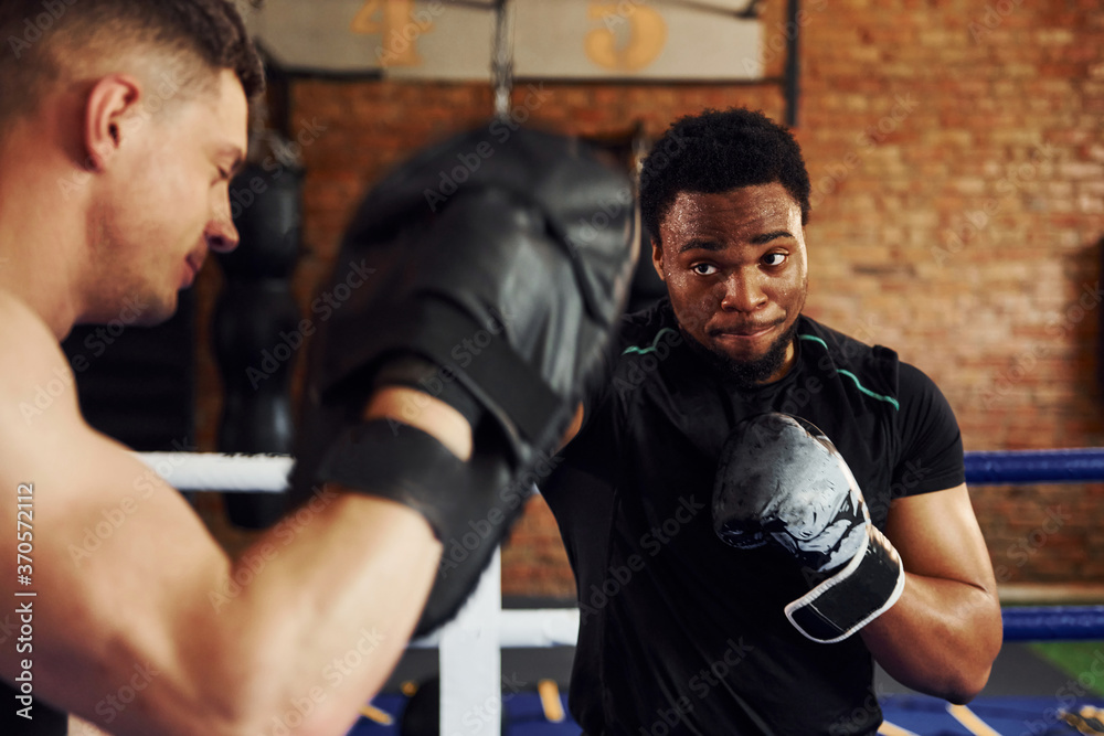 Having boxing practive. African american man with white guy have workout day in gym Having boxing practive. African american man with white guy have workout day in gym
