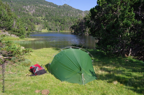 Tente de bivouac verte en montagne pour camper en camping au bord de l'eau du lac des Bouillouses avec sac à dos rouge