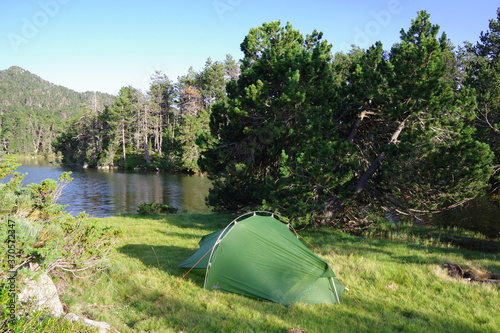 Tente verte de bivouac et de camping sur la pelouse en for  t au bord de l eau du lac de montagne