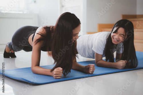 Happy mother and daughter exercising together.mother and daughter doing plank at home.