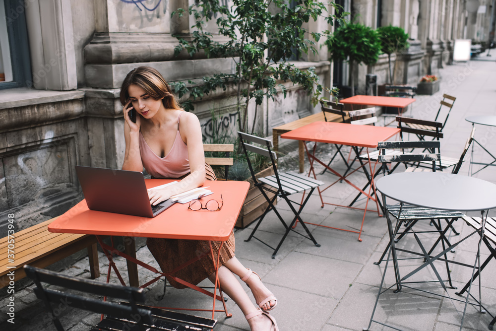 Concentrated woman with netbook and smartphone on cafe terrace Concentrated woman with netbook and smartphone on cafe terrace