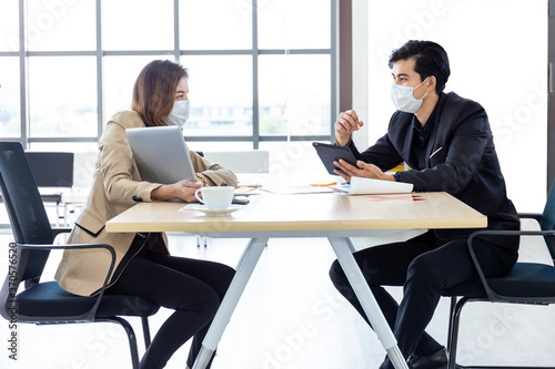 Business and social distancing sitting at the same table with a plastic shield.Office new normal lifestyle.