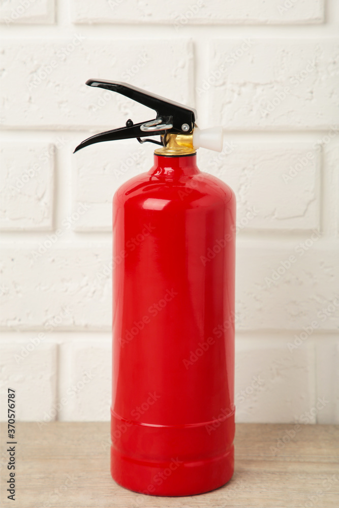 Obraz premium Fire extinguisher on white brick wall with clipping path. Vertical foto.