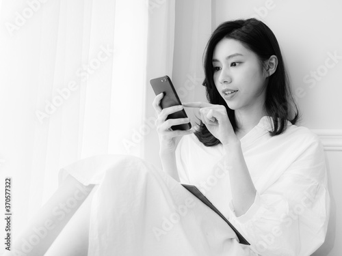 Young asian woman using smartphone at home in black and white photo