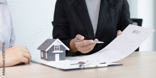 House salesman asks the customer to sign a house purchase contract and around the house with the keys.