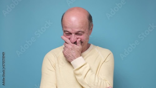 Senior man laughing and embarrassed giggle covering mouth with hands
