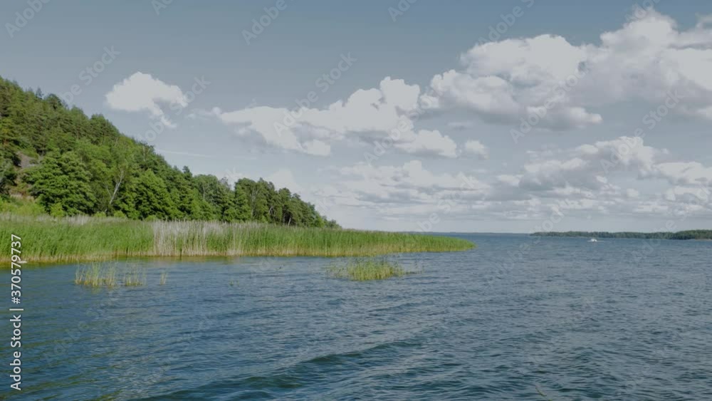 Beautiful nature landscape view. Gorgeous lake water surface, green forest trees and blue sky with white clouds background. Beautiful nature landscape view. Gorgeous lake water surface, green forest trees and blue sky with white clouds background.