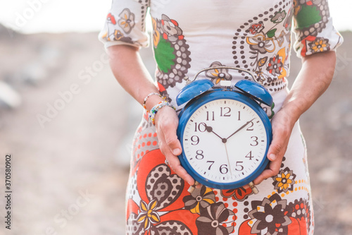 фотографія Concept of time and timeless lifestyle - unrecognizavble woman hold a clock on h