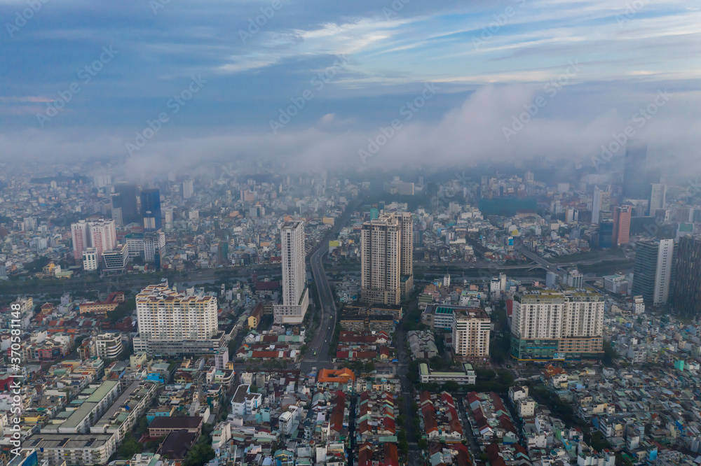 Aerial view of early morning fog in built-up urban area with high rise buildings and background obscured by low cloud