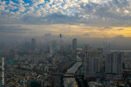 Beautiful aerial photo of colorful sunrise and morning fog in Ho Chi Minh City featuring the canal, bridges Saigon River and high rise buildings obscured by low cloud