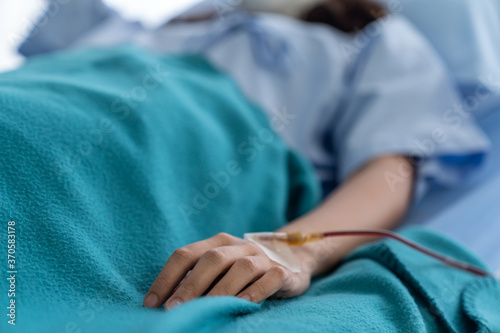 Hand woman with medical drip intravenous needle while lying on the ged at hospital.