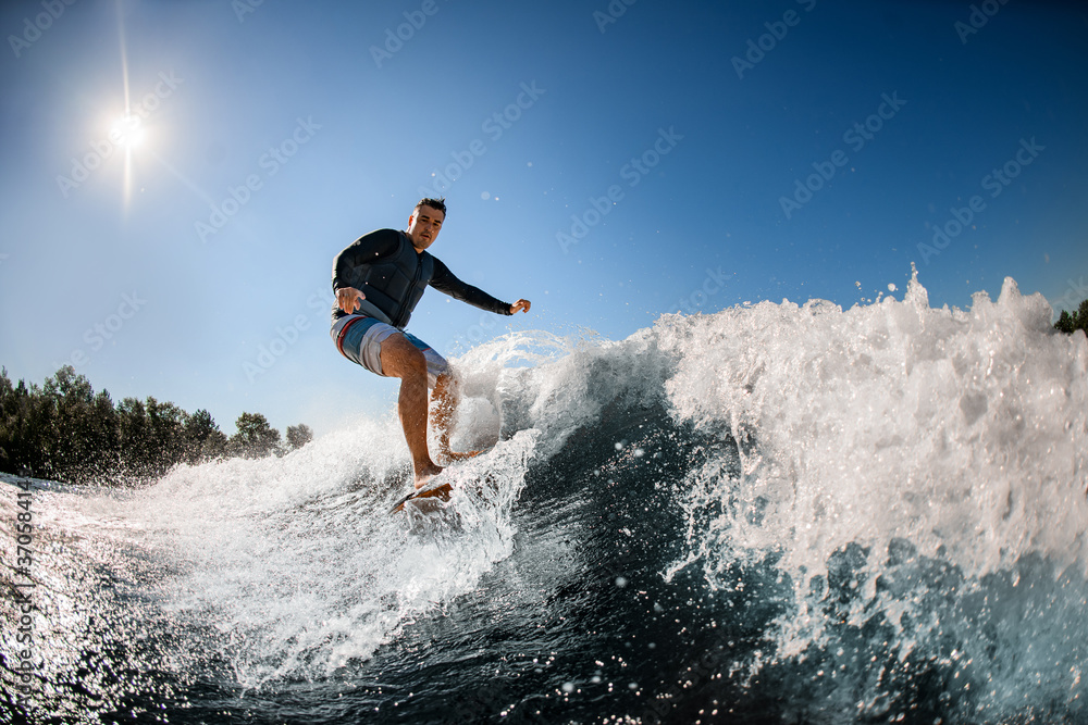 man in black swimming vest rides the wave on surfboard