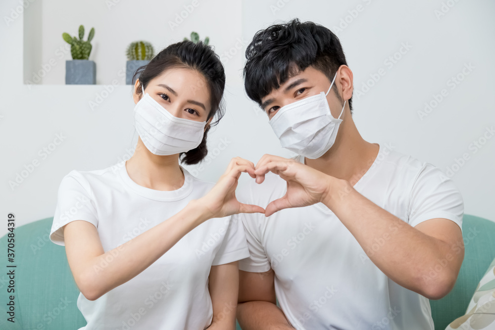 Asian couple wearing protective face mask and making shape of Heart by their Hands at home. Asian couple wearing protective face mask and making shape of Heart by their Hands at home.
