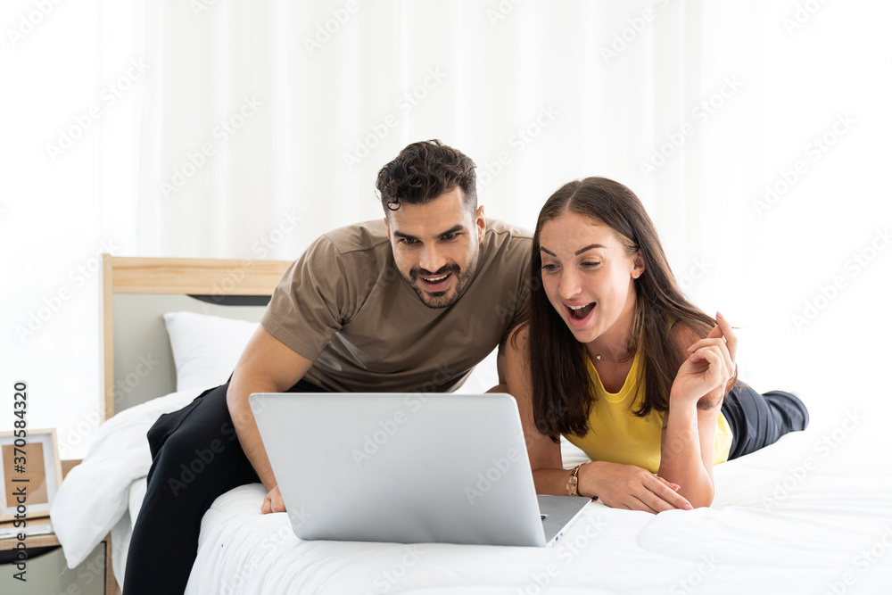 Young happy couple using laptop computer for video call or shopping online on the bed at home. Young happy couple using laptop computer for video call or shopping online on the bed at home.