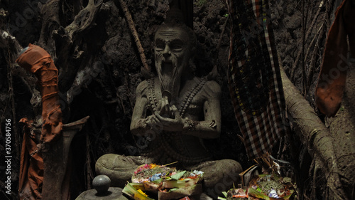 Religious place for rites with ancient statues of people in a dark cave with strong shadows
