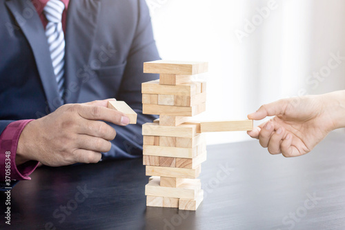 Business people collaborate towards wooden blocks The idea of doing business on risk is similar to connecting wooden blocks.