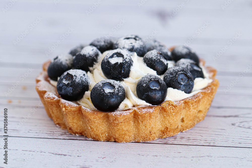 Close-up dough tartlet with creamy white cream and sweet blueberry. On a white background. Close-up dough tartlet with creamy white cream and sweet blueberry. On a white background.