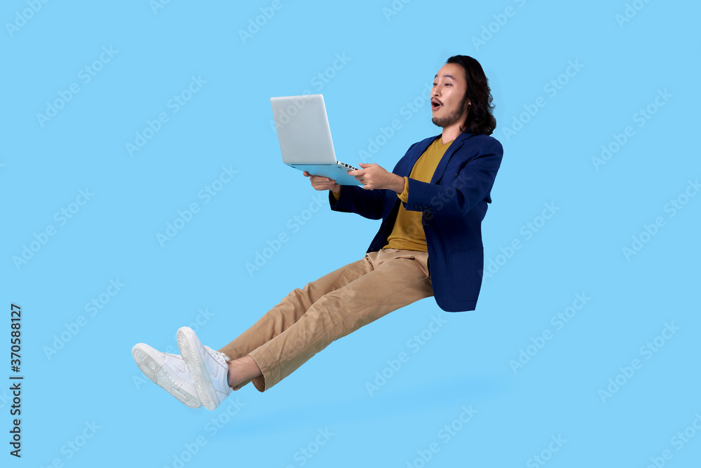 © NaMong Productions - Young asian businessman hand holding computer laptop floating in mid-air isolated on blue background. © NaMong Productions - Young asian businessman hand holding computer laptop floating in mid-air isolated on blue background.
