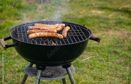 Delicious sausages frying on a grill outdoors.