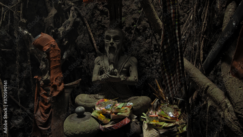 Religious place for rites with ancient statues of people in a dark cave with strong shadows Religious place for rites with ancient statues of people in a dark cave with strong shadows