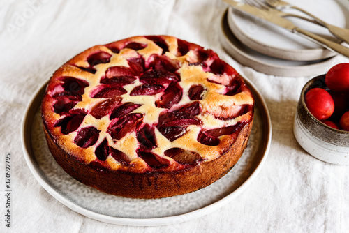 Homemade Ricotta Plum Cake on beige linen tablecloth. Cottage cheese casserole with vanilla, semolina and plums. Selective focus