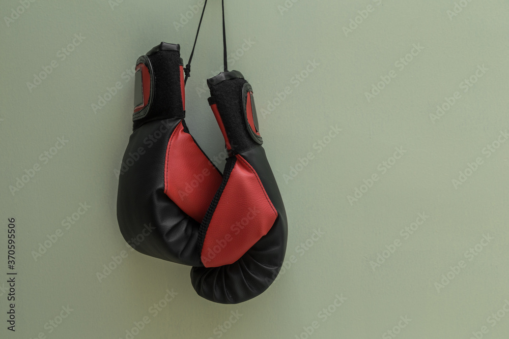 red and black boxing gloves hanging close up with a white background, studio