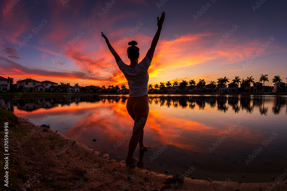 Fototapeta premium Silhouette of a woman on a sunset with reflections in the lake