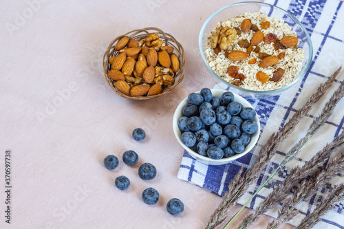 Bowls of granola, raisins, nuts and blueberries. Healthy breakfast every day. Copy space. Beige linen background. Flat lay