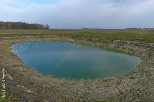 Small artificial shallow reservoir. A beautifully colored pond. Spring landscape.