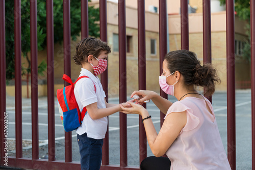 A woman putting hydro alcoholic gel on the hands of a child.