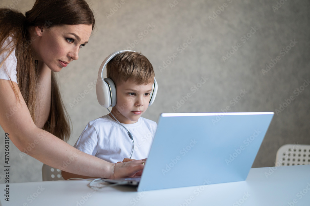 A caring mother helps her child do homework on a laptop. A woman and her little son are looking at a computer monitor. A caring mother helps her child do homework on a laptop. A woman and her little son are looking at a computer monitor.